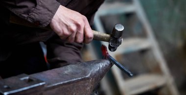 Onun forge, seçici odak üstünde metal bir parça işleme bir demirci elleri Close-up.