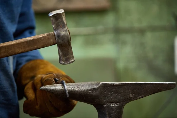 Close-up de um ferreiro mãos manipulando uma peça de metal acima de sua forja, foco seletivo . — Fotografia de Stock
