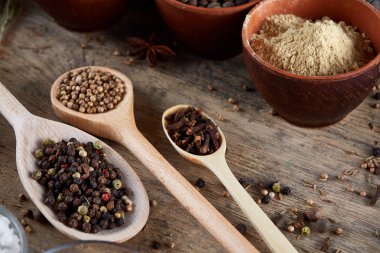 Tahta kaşık ve kase ve biraz tuz bir eski ahşap varil, üstten görünüm, yakın çekim, seçici odak içinde çeşitli baharatlar.