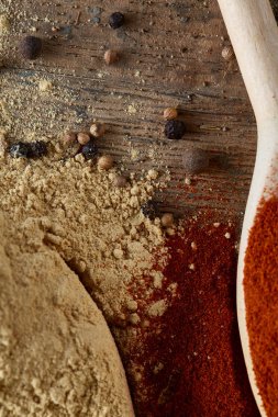 Paprica ve karabiber dolu bir tahta kaşıklar üstten görünüm ahşap varil arka plan, seçici odak üzerinde.