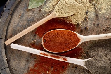 Tahta kaşık ve kase ve biraz tuz bir eski ahşap varil, üstten görünüm, yakın çekim, seçici odak içinde çeşitli baharatlar.