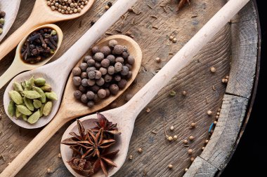 Aromatik kaşıklarla eski ahşap masa, yakın çekim, düz yemek pişirmek için çeşitli baharatlar yatıyordu, seçici odak.