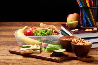 Okul veya sandviç ile öğle yemeği kutusu ve çeşitli renkli sebze ve meyve ahşap arka plan üzerinde piknik, yakın çekim.