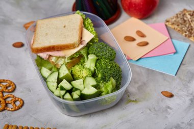 Okul veya sandviç ile öğle yemeği kutusu ve çeşitli renkli sebze ve meyve ahşap arka plan üzerinde piknik, yakın çekim.