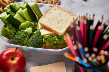 Okul veya sandviç ile öğle yemeği kutusu ve çeşitli renkli sebze ve meyve ahşap arka plan üzerinde piknik, yakın çekim.