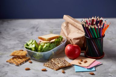 Okul veya sandviç ile öğle yemeği kutusu ve çeşitli renkli sebze ve meyve ahşap arka plan üzerinde piknik, yakın çekim.