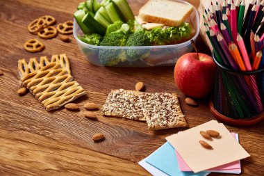 Okul öğle yemeği molası ile sağlıklı öğle yemeği kutusu ve okul malzemeleri ahşap masa, seçici odak kavramı.