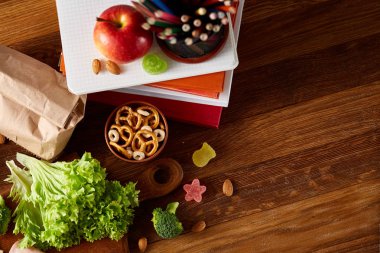 Okul öğle yemeği molası ile sağlıklı öğle yemeği kutusu ve okul malzemeleri ahşap masa, seçici odak kavramı.