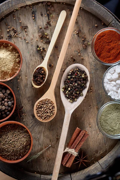 Tahta kaşık ve kase ve biraz tuz bir eski ahşap varil, üstten görünüm, yakın çekim, seçici odak içinde çeşitli baharatlar.