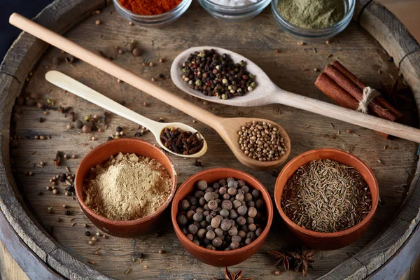 Tahta kaşık ve kase ve biraz tuz bir eski ahşap varil, üstten görünüm, yakın çekim, seçici odak içinde çeşitli baharatlar.