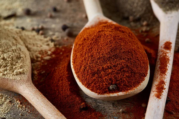 Paprica ve karabiber dolu bir tahta kaşıklar üstten görünüm ahşap varil arka plan, seçici odak üzerinde.