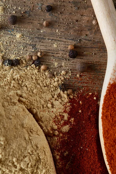 Paprica ve karabiber dolu bir tahta kaşıklar üstten görünüm ahşap varil arka plan, seçici odak üzerinde.