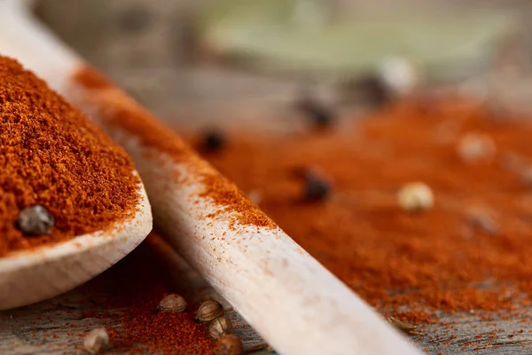 Paprica ve karabiber dolu bir tahta kaşıklar üstten görünüm ahşap varil arka plan, seçici odak üzerinde.