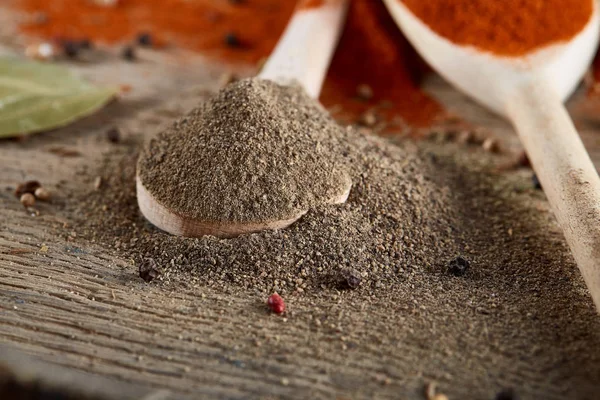 Tahta kaşık ve kase ve biraz tuz bir eski ahşap varil, üstten görünüm, yakın çekim, seçici odak içinde çeşitli baharatlar.