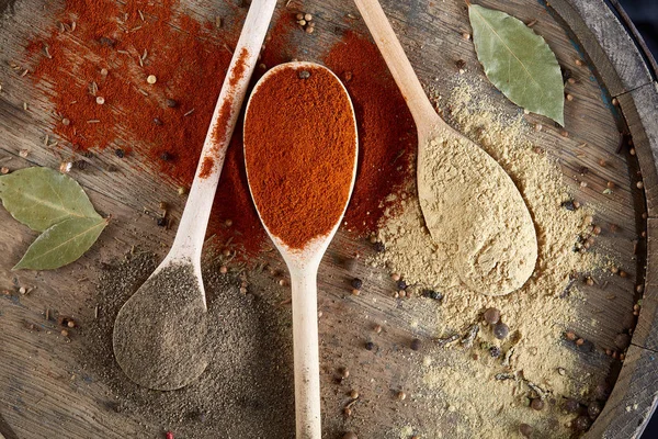 Tahta kaşık ve kase ve biraz tuz bir eski ahşap varil, üstten görünüm, yakın çekim, seçici odak içinde çeşitli baharatlar.