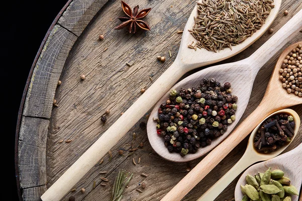 Aromatik kaşıklarla eski ahşap masa, yakın çekim, düz yemek pişirmek için çeşitli baharatlar yatıyordu, seçici odak.