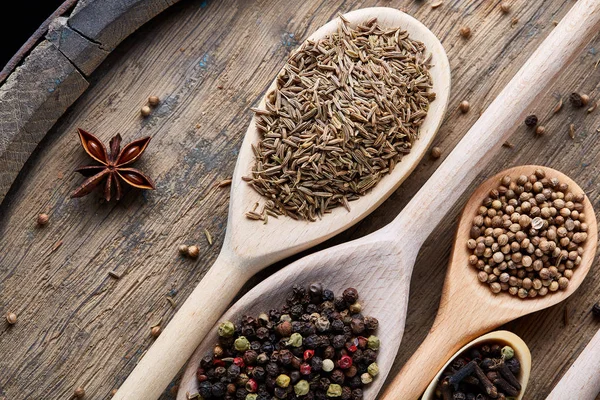 Aromatik kaşıklarla eski ahşap masa, yakın çekim, düz yemek pişirmek için çeşitli baharatlar yatıyordu, seçici odak.