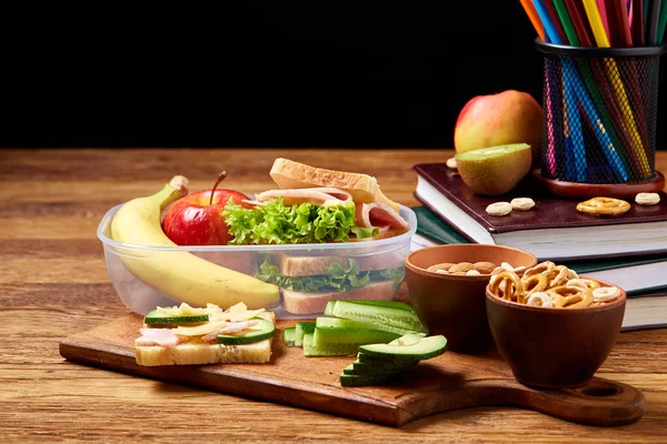 Okul veya sandviç ile öğle yemeği kutusu ve çeşitli renkli sebze ve meyve ahşap arka plan üzerinde piknik, yakın çekim.