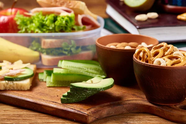 School of picknick doos van de lunch met broodje en diverse kleurrijke groenten en fruit op houten achtergrond, close-up. — Stockfoto