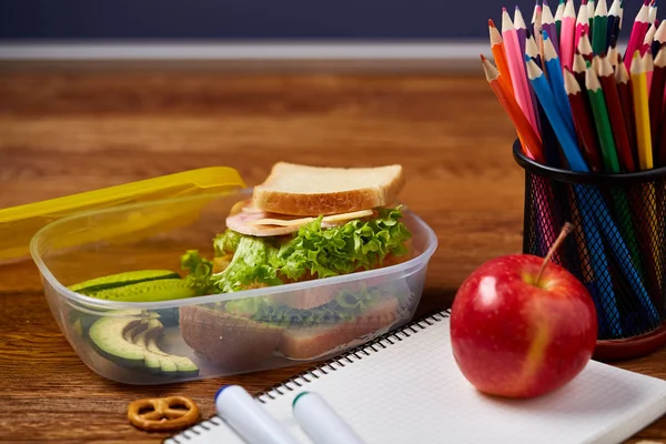 Beyaz masa, seçici odak sağlıklı öğle yemeği kutusu ve okul malzemeleri ile okul öğle yemeği molası kavramı.