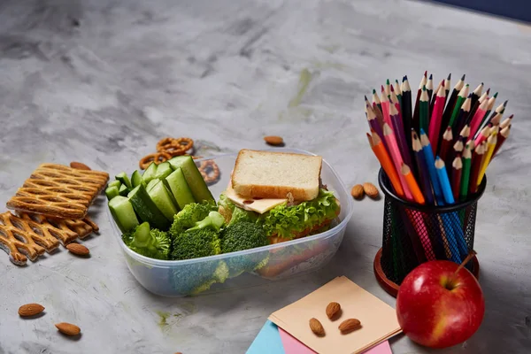 Beyaz masa, seçici odak sağlıklı öğle yemeği kutusu ve okul malzemeleri ile okul öğle yemeği molası kavramı.