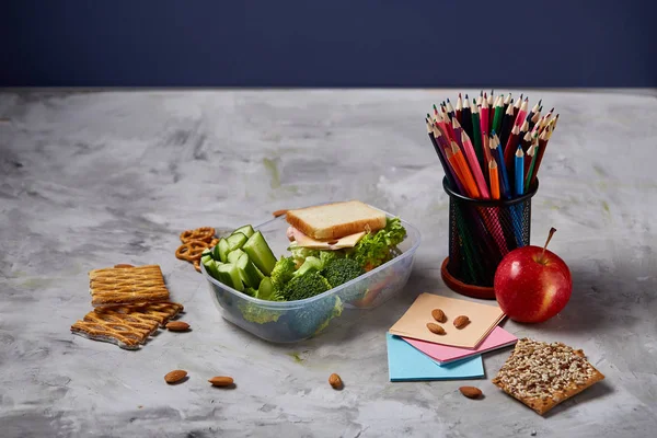 Beyaz masa, seçici odak sağlıklı öğle yemeği kutusu ve okul malzemeleri ile okul öğle yemeği molası kavramı.