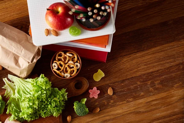 Okul öğle yemeği molası ile sağlıklı öğle yemeği kutusu ve okul malzemeleri ahşap masa, seçici odak kavramı.