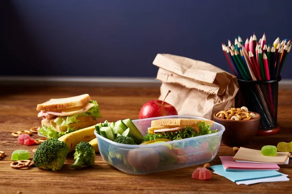 Beyaz masa, seçici odak sağlıklı öğle yemeği kutusu ve okul malzemeleri ile okul öğle yemeği molası kavramı.