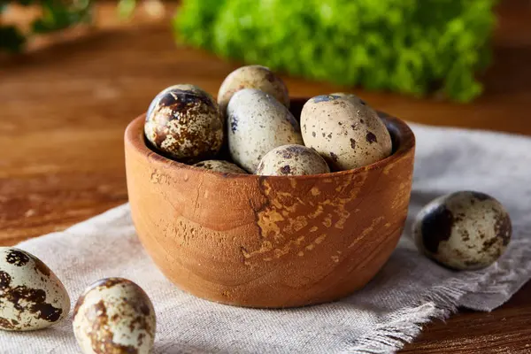 Bıldırcın yumurtası yeşil peçeteyle kutusunda bulanık doğal yaprakları arka plan, seçici odak, yakın çekim