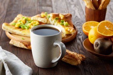 Sabah bir fincan kahve, breadsticks, meyve pasta ve ahşap zemin üzerine portakal konseptiyle.