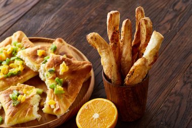 Sabah bir fincan kahve, breadsticks, meyve pasta ve ahşap zemin üzerine portakal konseptiyle.