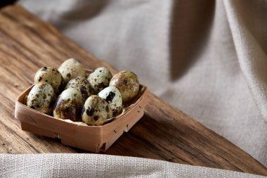 Ahşap saf masa örtüsü, yakın çekim, yüksek açılı görünüş, seçici odak parçası üzerinde kapsayıcısında bıldırcın yumurtası.