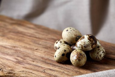 Grup üç bıldırcın odun parçası üzerinde yumurta saf masa örtüsü, üstten görünüm, seçici odak, arka ışık üzerinde.