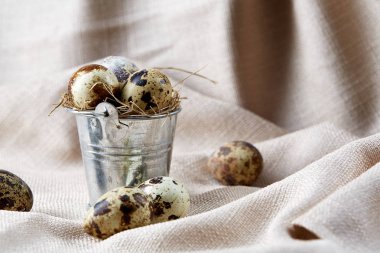 Küçük dekoratif kova peçete bıldırcın yumurtalarının dolu beyaz dokulu arka plan, yakın çekim, seçici odak üzerinde.