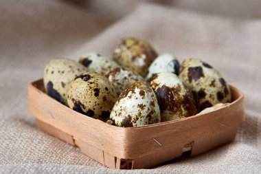 Küçük dekoratif kova peçete bıldırcın yumurtalarının dolu beyaz dokulu arka plan, yakın çekim, seçici odak üzerinde.