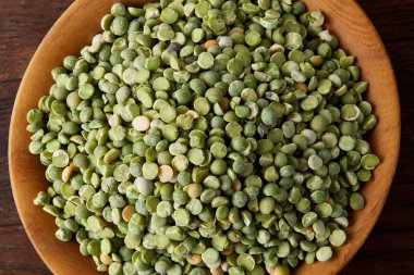 Rustik arka plan, yakın çekim, seçici odak, sığ derinlik-in tarla ahşap bir plaka üzerinde ham yeşil bezelye.