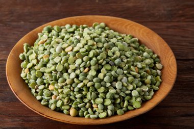 Rustik arka plan, yakın çekim, seçici odak, sığ derinlik-in tarla ahşap bir plaka üzerinde ham yeşil bezelye.