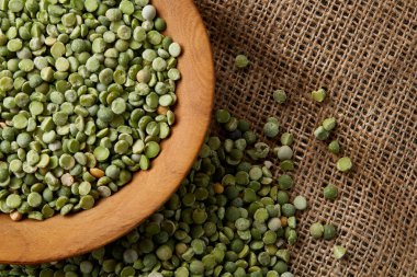 Çuval bezi masa örtüsü, yakın çekim, seçici odak, üstten görünüm ahşap bir plaka üzerinde ham yeşil bezelye.