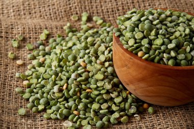 Çuval bezi masa örtüsü, yakın çekim, en iyi görünüm, seçici odak, sığ derinlik-in tarla yeşil bezelye ile devrilmiş bir kase.