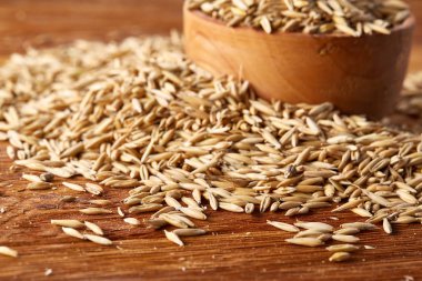 Ahşap arka plan, üstten görünüm, yakın çekim, makro, sığ derinlik-in tarla soyulmamış yulaf taneleri yığını.