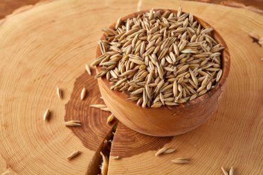 Ahşap arka plan, üstten görünüm, yakın çekim, makro, sığ derinlik-in tarla soyulmamış yulaf taneleri yığını.