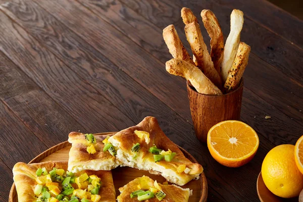 Sabah bir fincan kahve, breadsticks, meyve pasta ve ahşap zemin üzerine portakal konseptiyle.