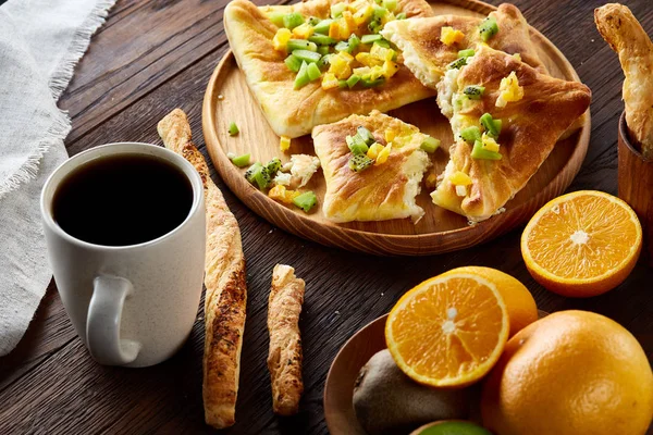 Sabah bir fincan kahve, breadsticks, meyve pasta ve ahşap zemin üzerine portakal konseptiyle.