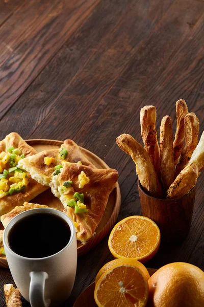 Sabah bir fincan kahve, breadsticks, meyve pasta ve ahşap zemin üzerine portakal konseptiyle.