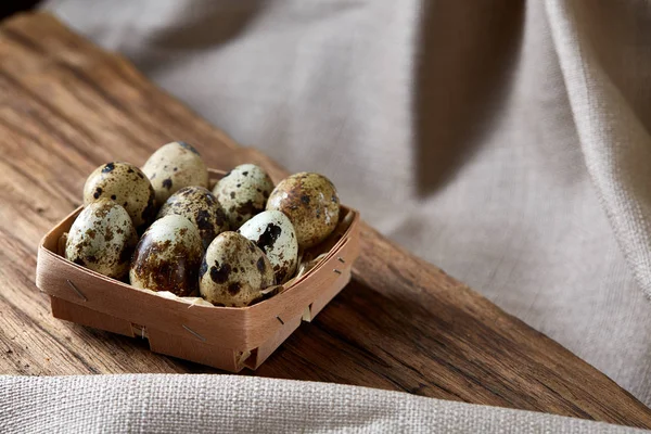 Ahşap saf masa örtüsü, yakın çekim, yüksek açılı görünüş, seçici odak parçası üzerinde kapsayıcısında bıldırcın yumurtası.