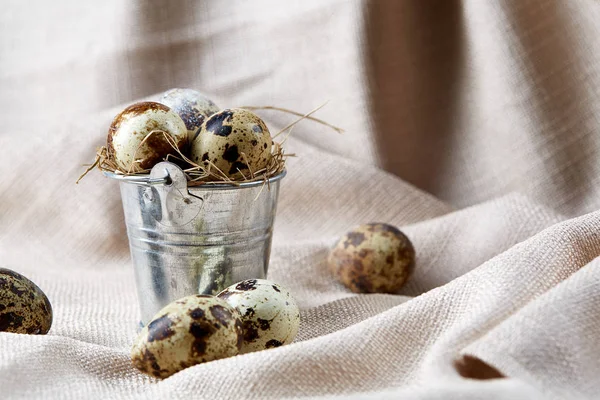 Küçük dekoratif kova peçete bıldırcın yumurtalarının dolu beyaz dokulu arka plan, yakın çekim, seçici odak üzerinde.