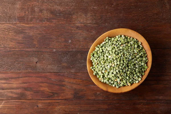 Rustik arka plan, yakın çekim, seçici odak, sığ derinlik-in tarla ahşap bir plaka üzerinde ham yeşil bezelye.