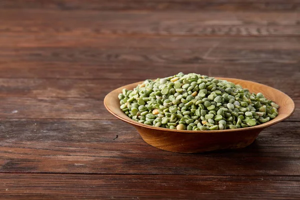 Rustik arka plan, yakın çekim, seçici odak, sığ derinlik-in tarla ahşap bir plaka üzerinde ham yeşil bezelye.