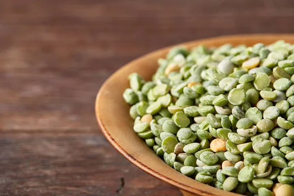 Rustik arka plan, yakın çekim, seçici odak, sığ derinlik-in tarla ahşap bir plaka üzerinde ham yeşil bezelye.