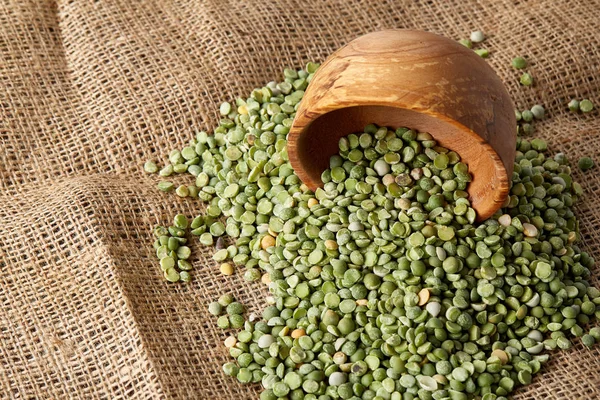 Çuval bezi masa örtüsü, yakın çekim, en iyi görünüm, seçici odak, sığ derinlik-in tarla yeşil bezelye ile devrilmiş bir kase.